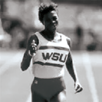 Black‑and‑white photo of a runner wearing a WSU uniform, mid‑stride on a track
