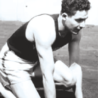 High‑contrast black‑and‑white image of a muscular track sprinter bent forward at the starting position, with arms and legs prominently defined.