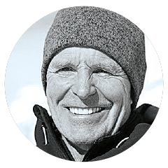 Circular headshot of a man wearing a knit hat and jacket, framed by a light border against an outdoor background.