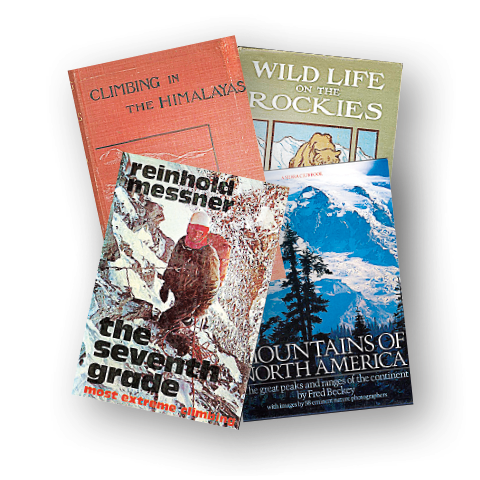 Stack of mountaineering and nature books, including visible titles about climbing in the Himalayas, wildlife in the Rockies, and North American mountains.