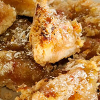 Close-up of sliced rhubarb crumb bars with jammy filling, golden crust, and powdered sugar on a plate.