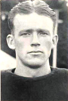 Historic black-and-white portrait of a football player wearing an early-era football uniform, shown from the shoulders up.