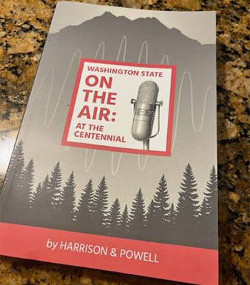 Book titled Washington State on the Air: At the Centennial featuring a microphone illustration, mountain silhouette, and forest graphic on the cover.