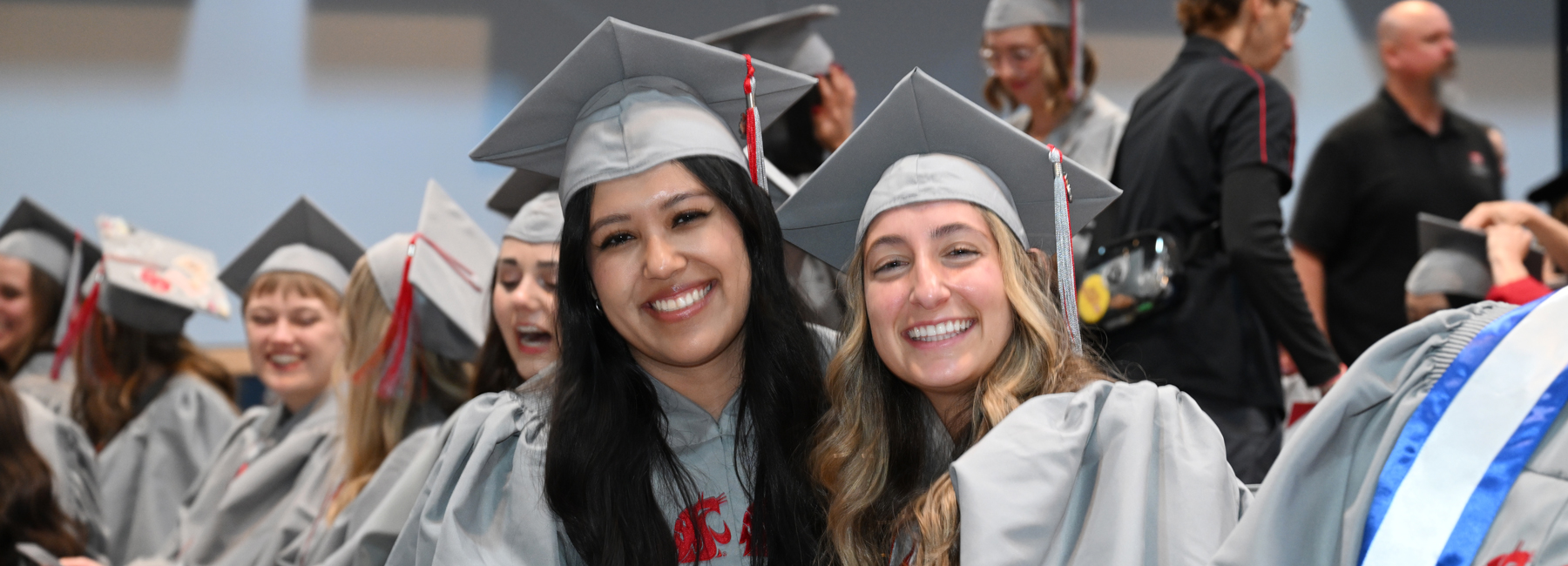Two smiling graduates in their regalia.
