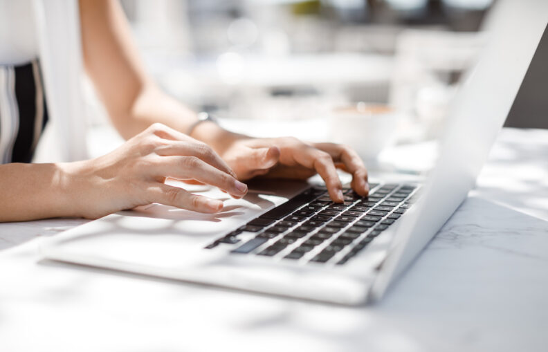 Woman typing on a laptop.
