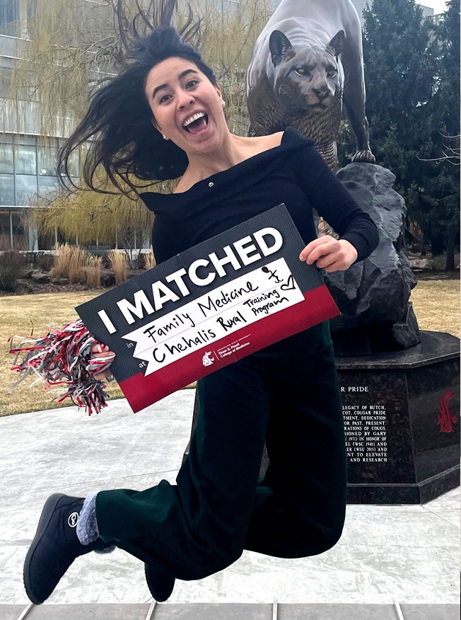 Laura Lopez leaps for joy in front of Cougar statue