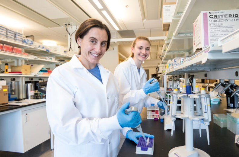 Researcher Lucia Peixoto in her lab with a grad student filling test tubes with samples.