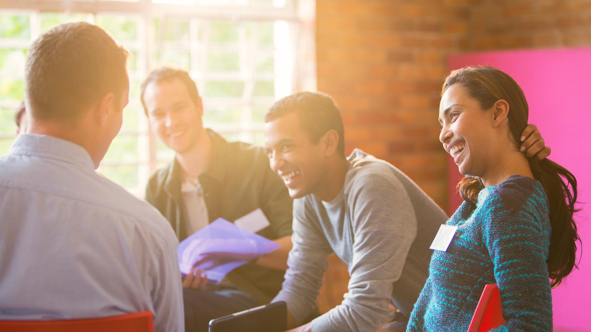 4 people sitting in a circle smiling during a group therapy session.