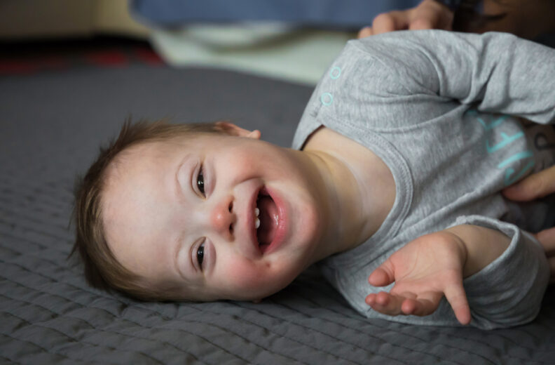 Happy baby laying on the floor on their side.
