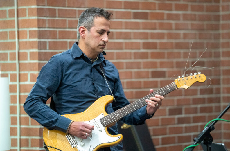Professor playing guitar as part of the faculty band.