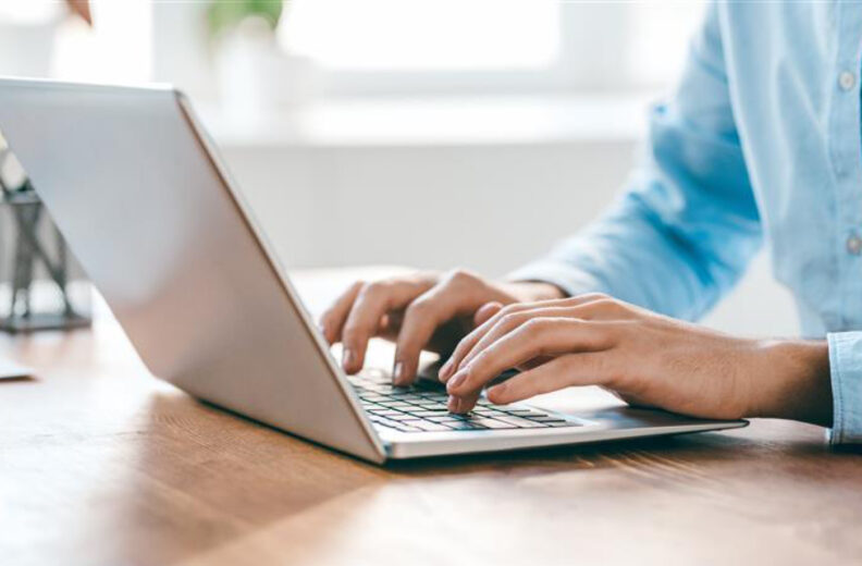 A person at a desk typing on a laptop.