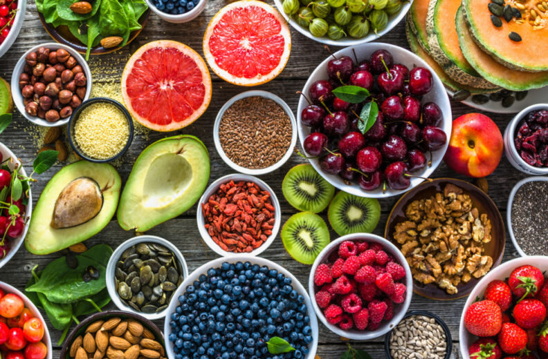 A table with different fruits ,nuts and grains spread on it.
