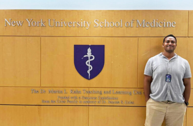 A man standing in front of the New York University School of Medicine sign.
