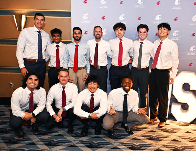 Group of 11 MD Students smiling in front on a WSU banner.