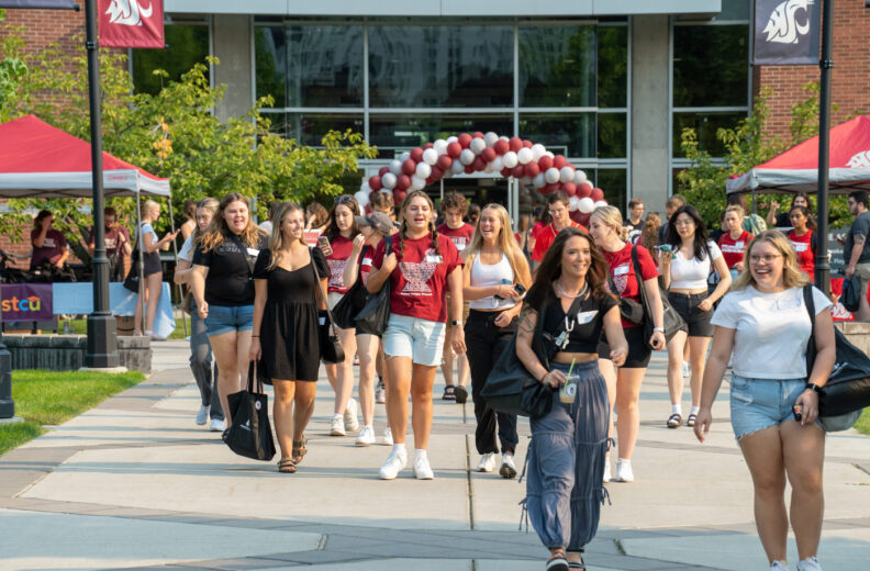 Outside with multiple student walking and talking outside of a Washington State University building.