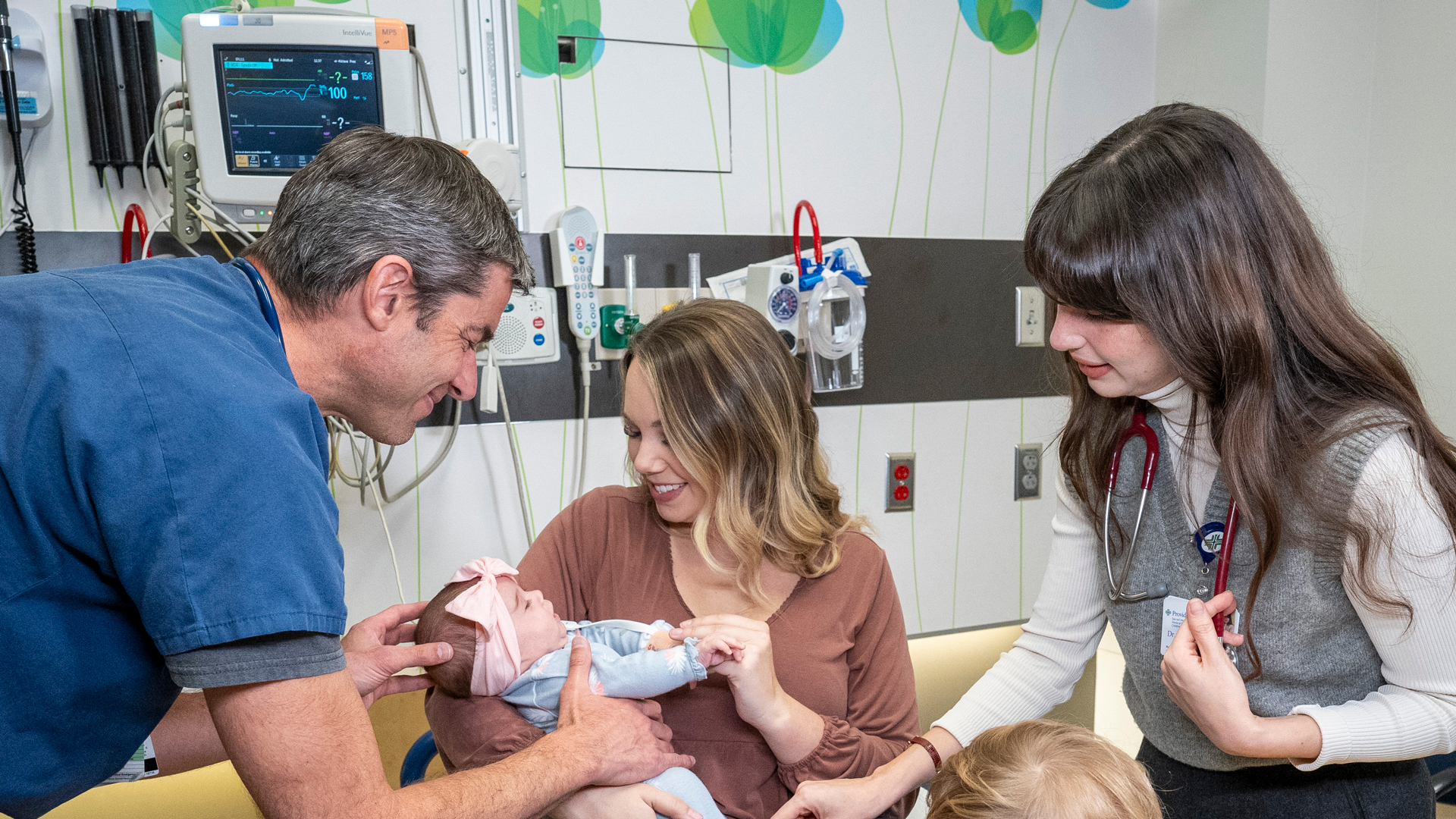 Doctor and resident helping a mother and child in an exam room in the hospital.