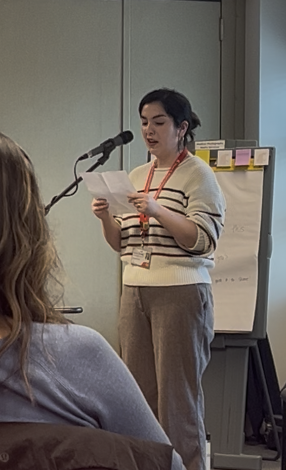 A person standing in front of a mic reading off of a piece of paper.