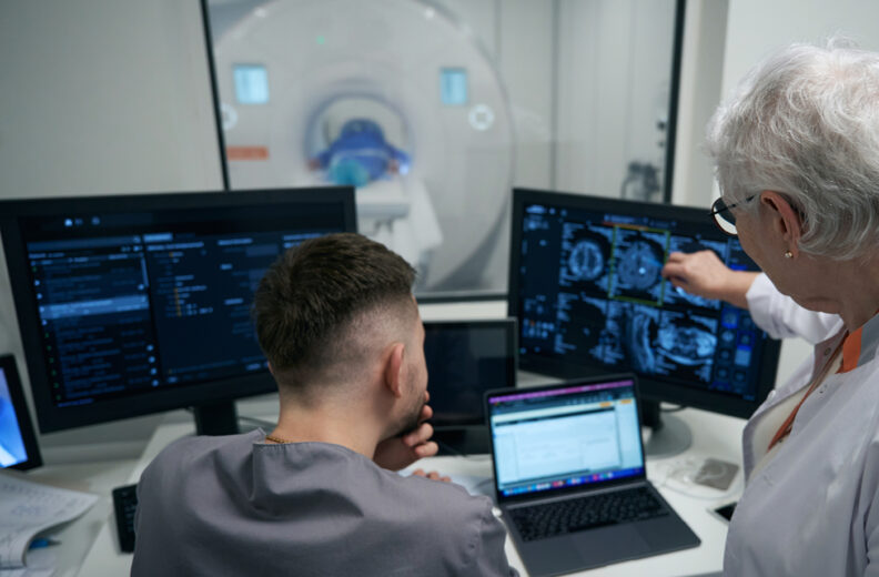 Two people looking at brain scans on a computer.