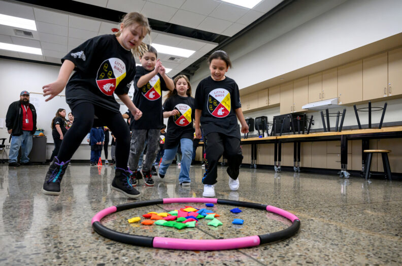 Kids running over to a hula hoop that has bean bags inside the hoop.