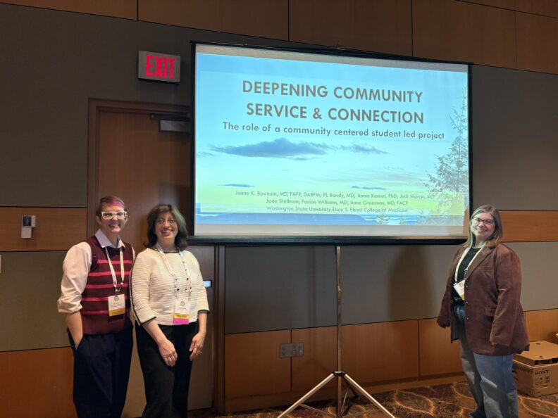 Three presenters stand in front of a projection screen displaying a presentation titled ‘Deepening Community Service & Connection’ in a conference room.