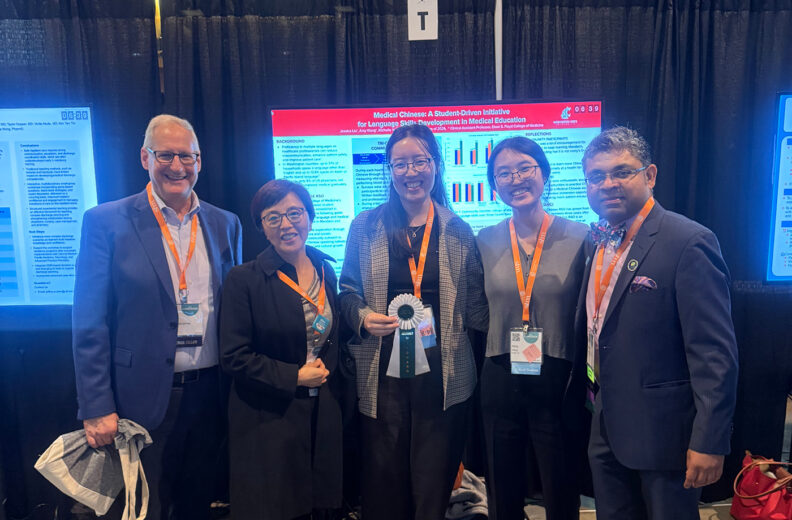 Five conference attendees pose in front of a research poster, with one holding an award ribbon.