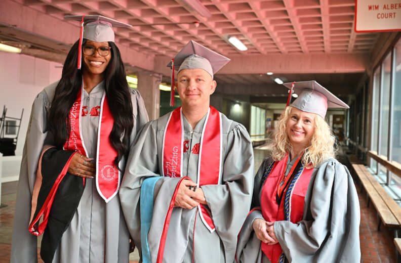 Three graduates smiling standing next to each other.