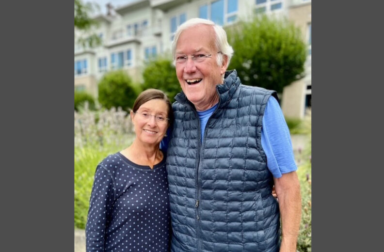 Two older people smiling standing side by side.