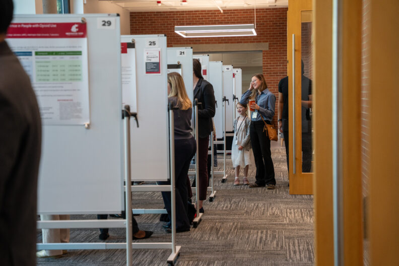 Attendees walk through a poster session area lined with research displays.