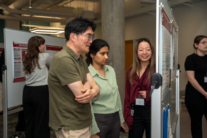 Attendees review a research poster during Student and Resident Research Day.