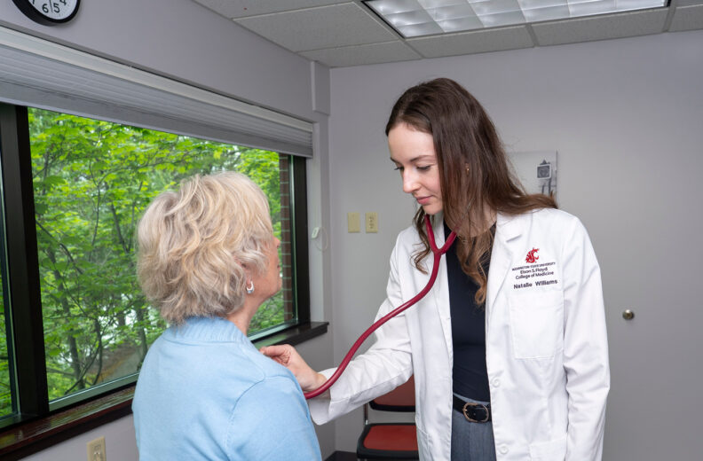Healthcare provider uses a stethoscope to check an older adult’s heart rate.
