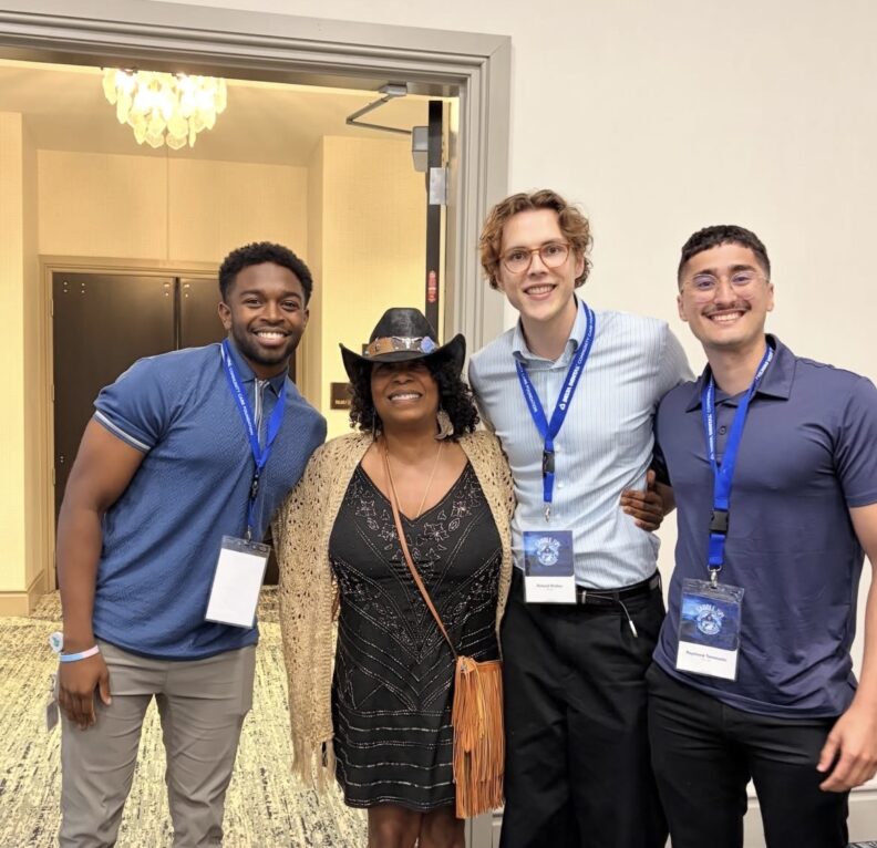 Four people smiling arm in arm.