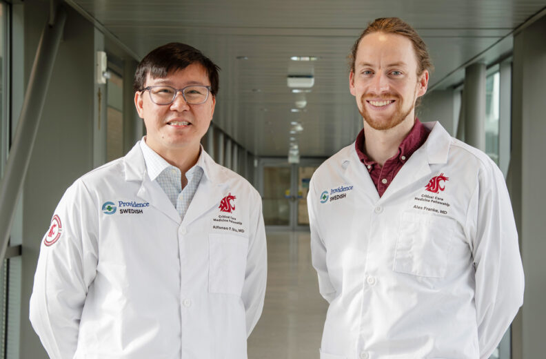 Two critical care fellows standing in the hospital smiling. 