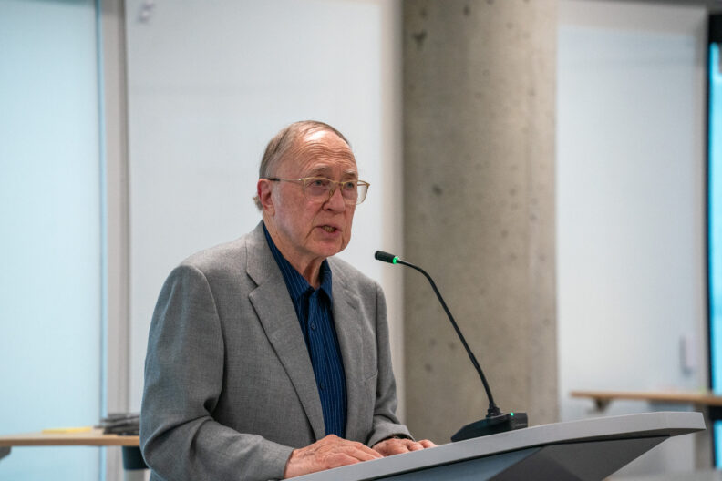 An elderly gentleman standing and speaking at a podium. 