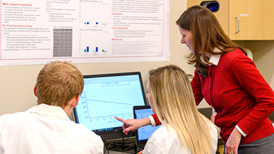 Professor showing two students a graph on a computer in Speech Lab