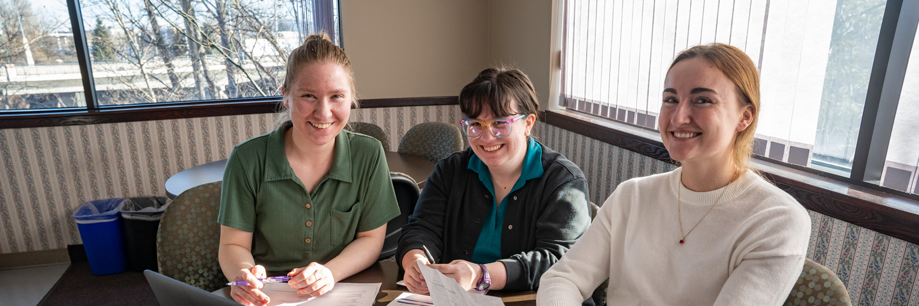 Three student around a table looking at paperwork