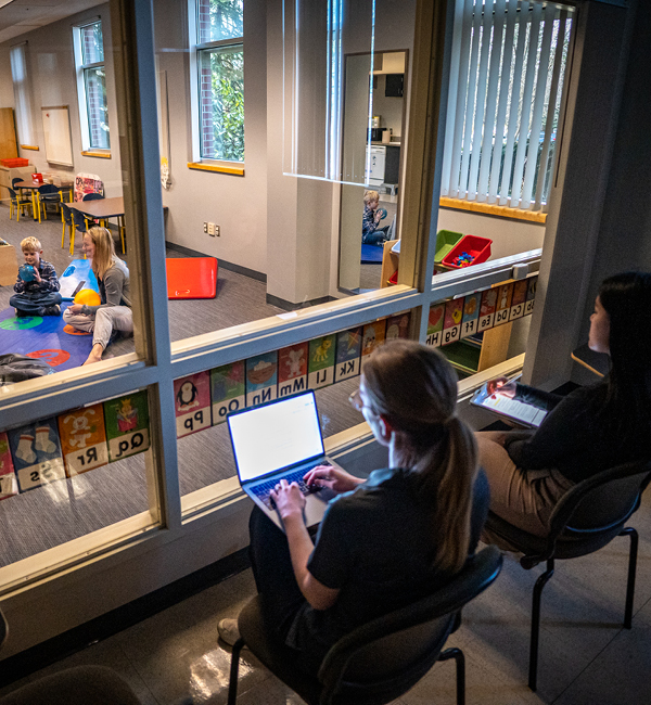 Researchers observing two children in ASD Clinic