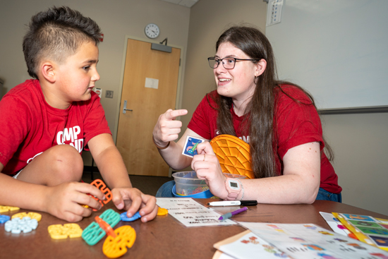 SHS Graduate student working with a child at camp candoo with flash cards.