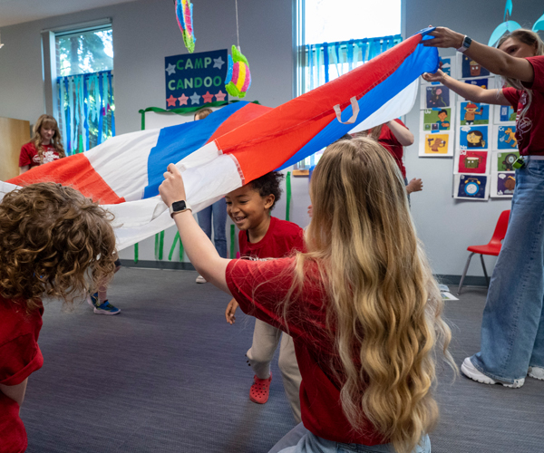 Camp candoo camper running under parachute.