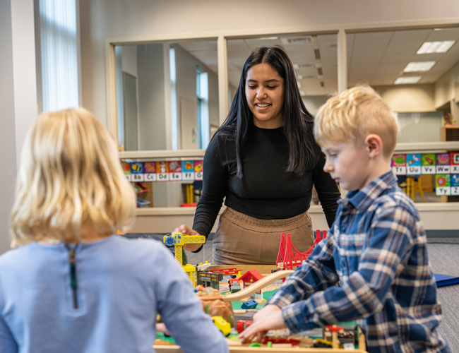 Graduste student working with 2 children in the ASD clinic playing with toys.