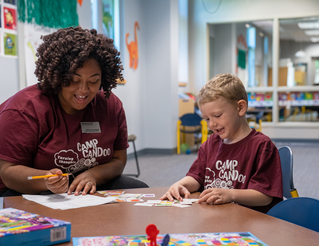 Graduate student coloring with a camper at Camp Candoo.