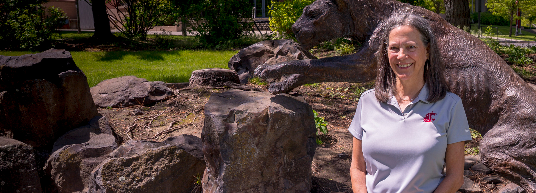 Karyn Discoll Teague sitting outside on the Spokane campus in front of the cougar statue.