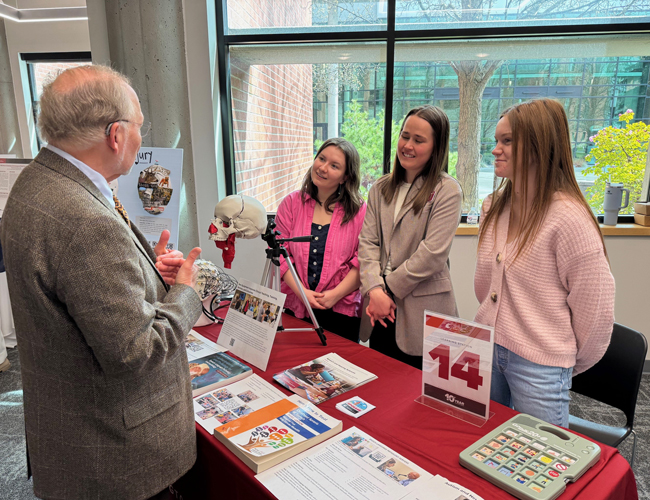3 SHS students talking at a trade table talking about the SHS program.