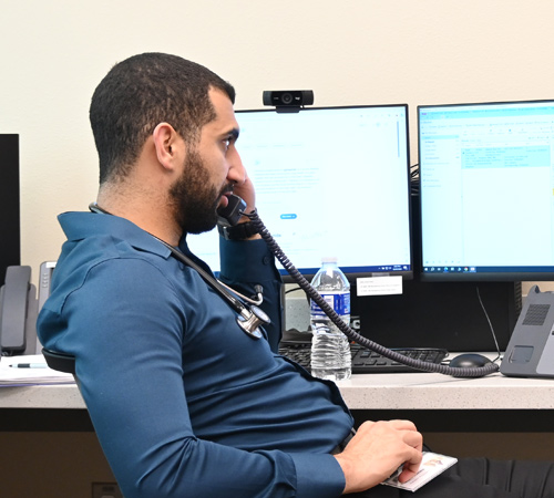 Resident talking on phone sitting in front of a dual monitor computer