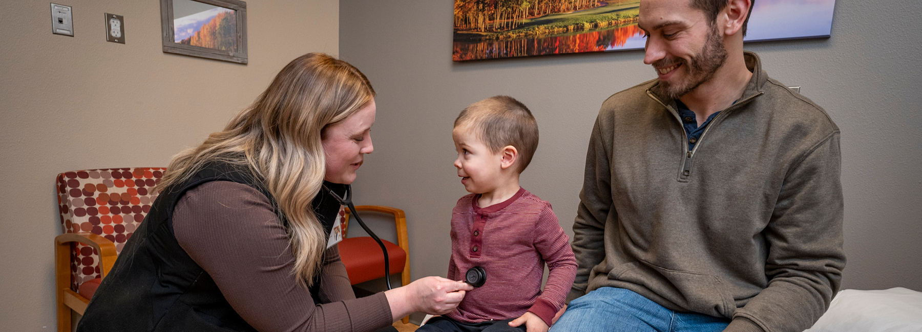 Family medicine resident giving a child an exam while his dad sits on the table with him.