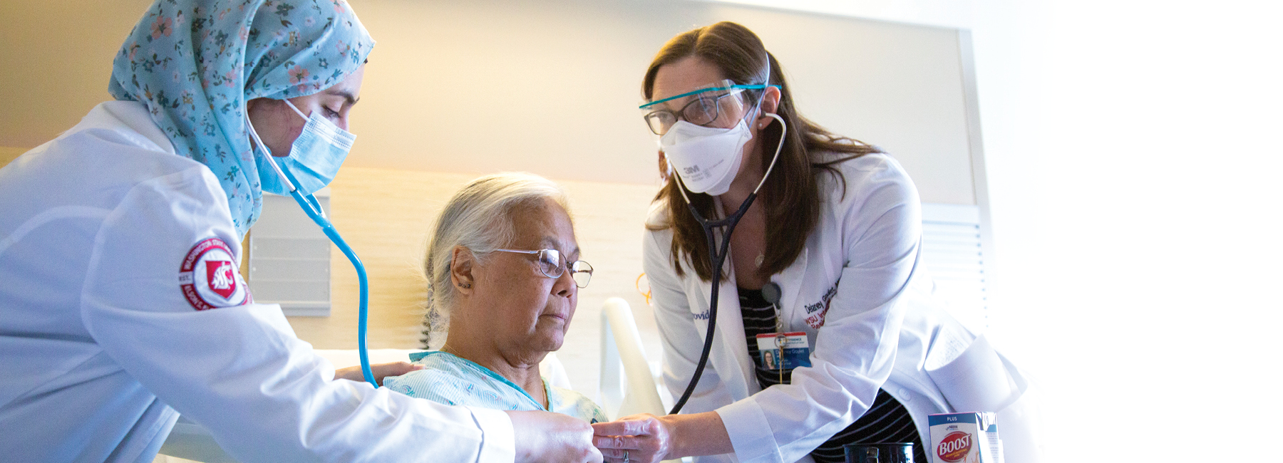 Two doctors with a patient, checking their heart rate.
