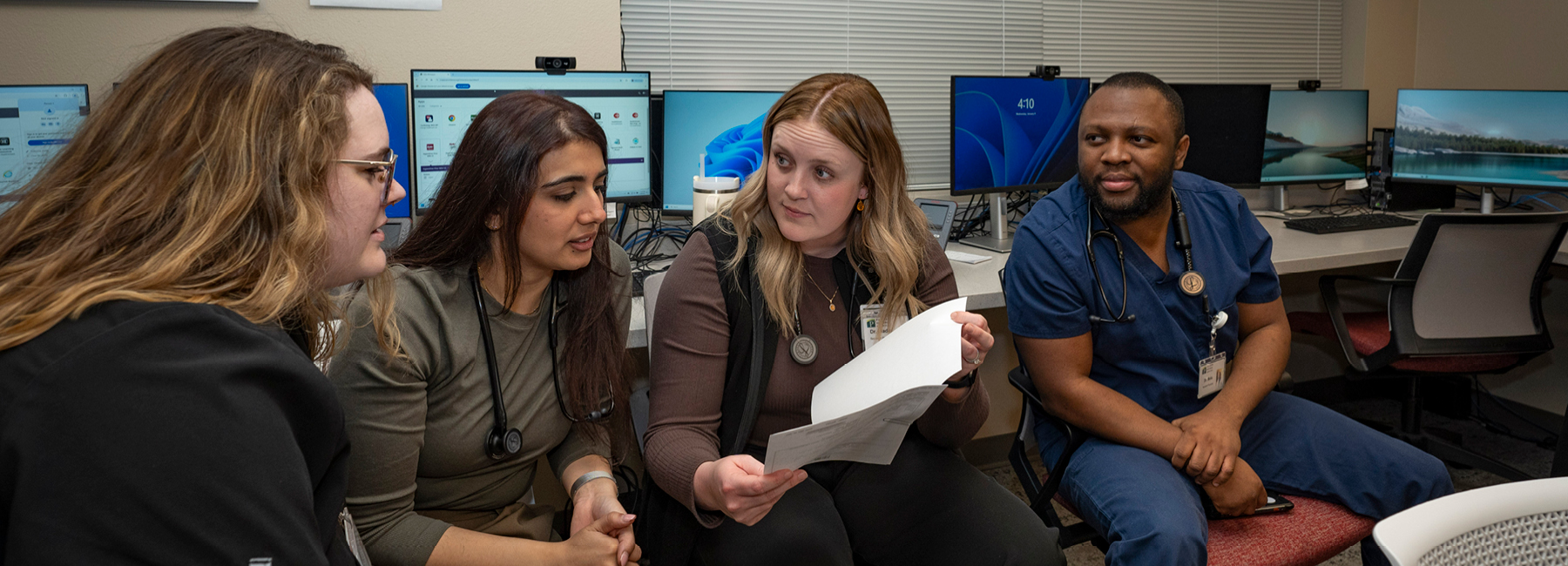 4 residents sitting gathered together reading a paper.