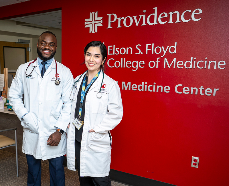 Two residents smiling and standing in the clinic waiting room.