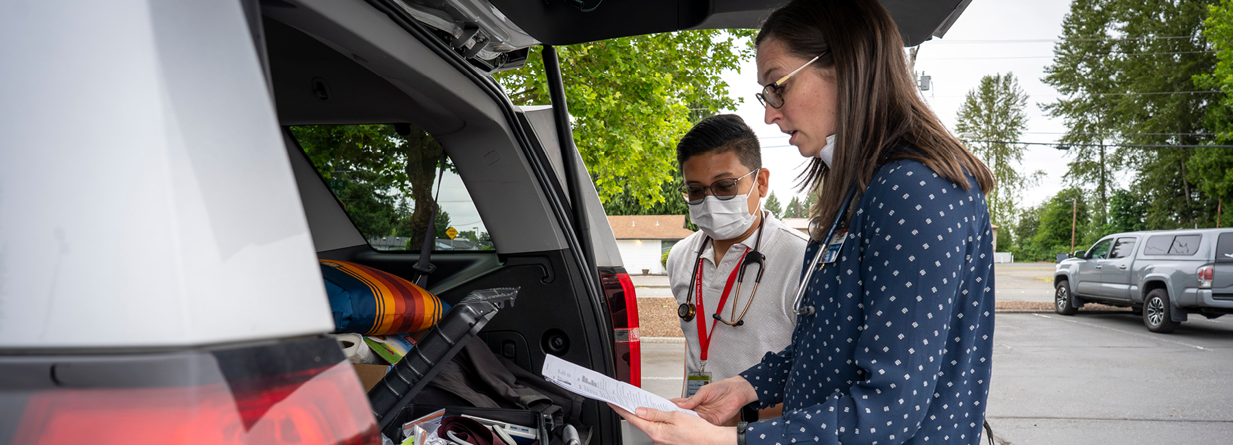 Doctor and resident getting medical supplies out of the back of a vehicle.