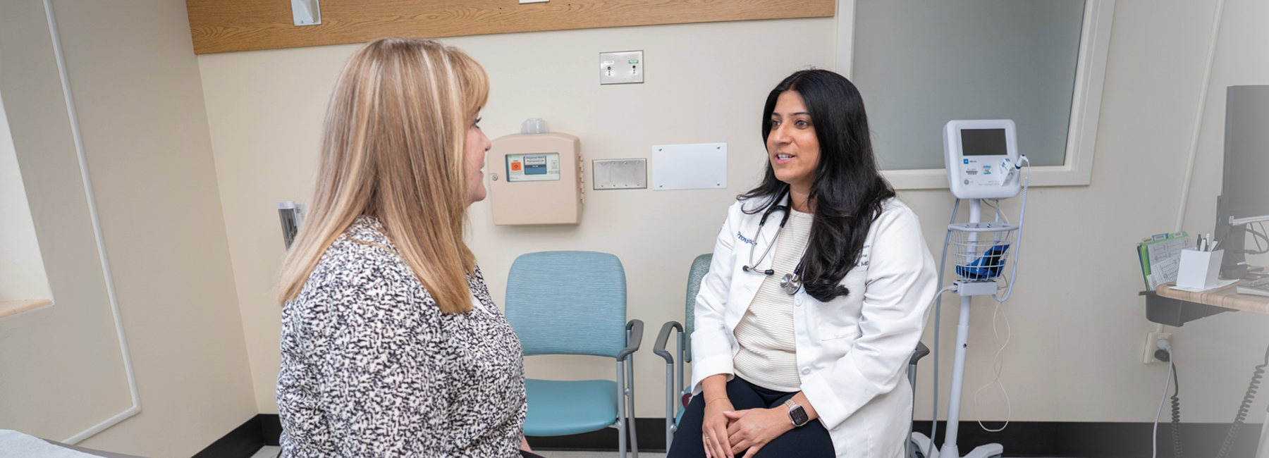 Resident talking with patient in a clinic exam room.