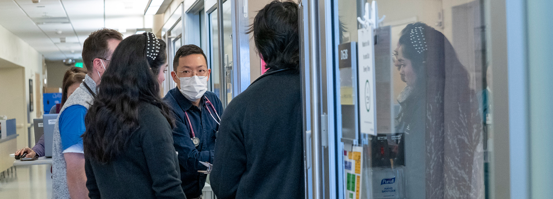 Group of six doctors in the hallway of the hospital having a meeting.